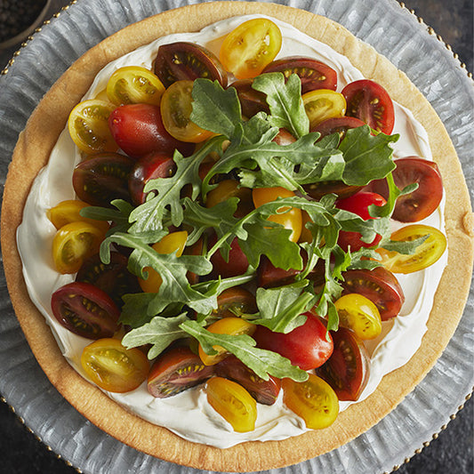 Slice of savoury pie with almond pie crust, cream cheese filling, topped with arugula and cherry tomato